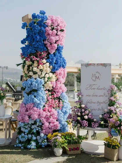 A personalized welcome sign for the wedding ceremony, adorned with a stunning arrangement of pink and blue hydrangeas. This is the first beautiful detail guests see as they arrive.