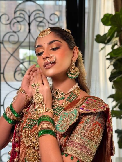 Adjusting the jewellery is part of the process. The makeup is designed to harmonize with the heavy, intricate gold jewellery, creating a balanced and stunning look.