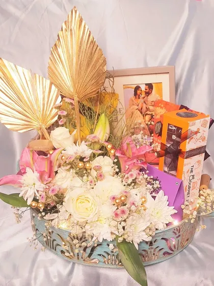 Another angle of our fresh floral gift hamper. The combination of white and pink flowers, golden palm leaves, and a personal photo makes this a stunning centerpiece and a heartfelt present.