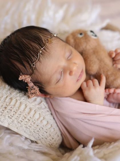 This sweet little lady is cuddling a tiny teddy bear. It's a heartwarming way to show just how small and delicate she is.