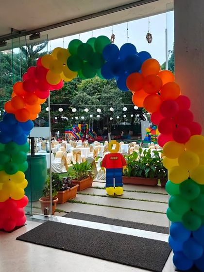 A rainbow balloon archway with a Lego character welcomes guests to this fun-filled birthday party.