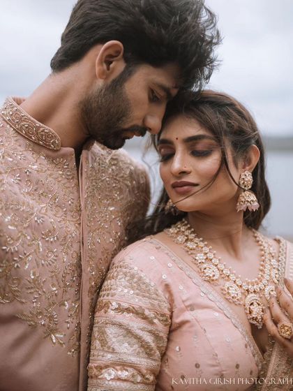 A close-up portrait of a couple in elegant pink traditional attire, capturing a moment of quiet intimacy and shared thought.