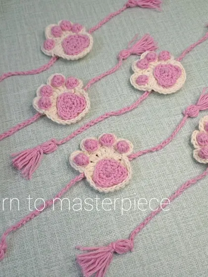 For the sibling who loves animals. This is my paw print rakhi, featuring a cute pink and white paw design with braided ties and tassels.