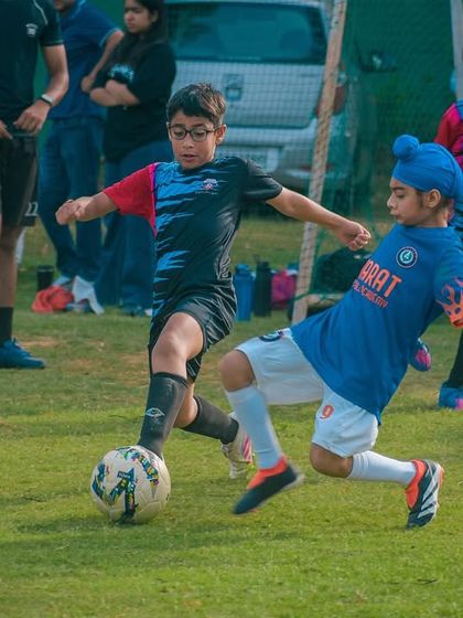 Two young players, one in a turban, compete fiercely for the ball, showcasing the diversity and inclusivity of our academy.