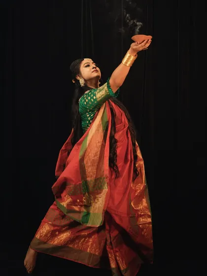 Another artistic shot with the diya, capturing the grace and devotion of the moment against a black backdrop.