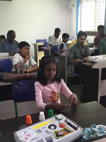 Here you can see the fun in action. Students, both young and old, are getting hands-on with their personal magic kits, practicing the cups and balls trick. This is what my workshops are all about: interactive learning for everyone.