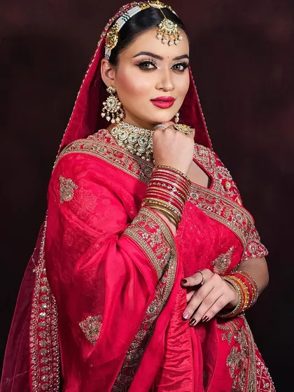 A full-length view of a bride in a red saree, demonstrating how the makeup complements the entire bridal ensemble.