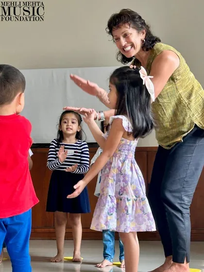 A teacher and students interact during a musical game. These playful exchanges build rapport and create a positive, encouraging learning atmosphere.