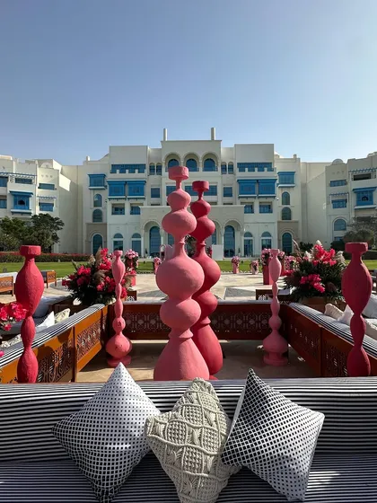 A glimpse of the Salwa Beach celebrations in Doha. The lounge seating, with its modern black-and-white cushions, looks out onto a courtyard filled with unique pink sculptural art.