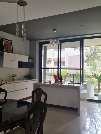 This open-plan dining and kitchen area is perfect for modern living. The white kitchen island with a sink faces the dining table, allowing for easy interaction between spaces.