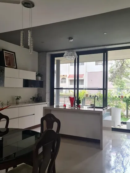 This open-plan dining and kitchen area is perfect for modern living. The white kitchen island with a sink faces the dining table, allowing for easy interaction between spaces.