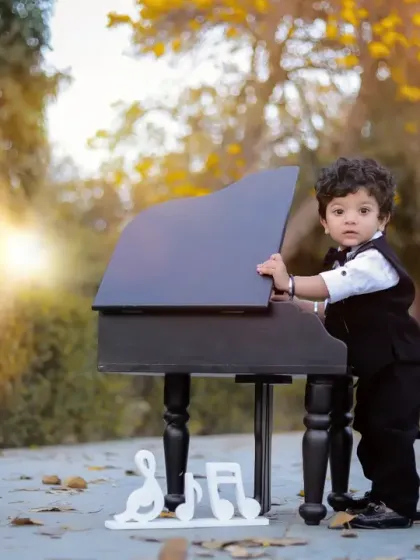 A different angle of our little pianist, showing his curiosity as he stands by the miniature piano. This pose adds variety to the gallery from a single session.