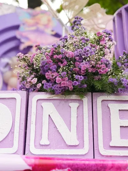 "ONE" blocks decorated with purple flowers, a lovely detail from Nishvika's enchanted garden party.