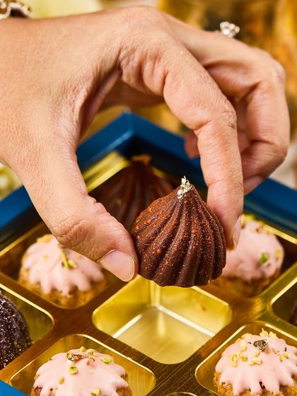 A hand selecting a Modak Bonbon from our festive gift box. Each one is a tiny work of art, finished with a touch of edible gold leaf.