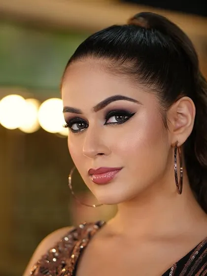 A full view of the red carpet glam look, with a sleek high ponytail and dramatic makeup against a bokeh background.