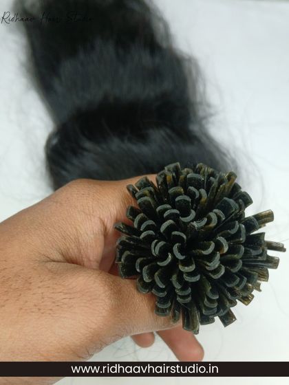 A hand holding a bundle of our U-Tip wavy extensions, highlighting the pre-bonded tips that ensure a secure and long-lasting installation.