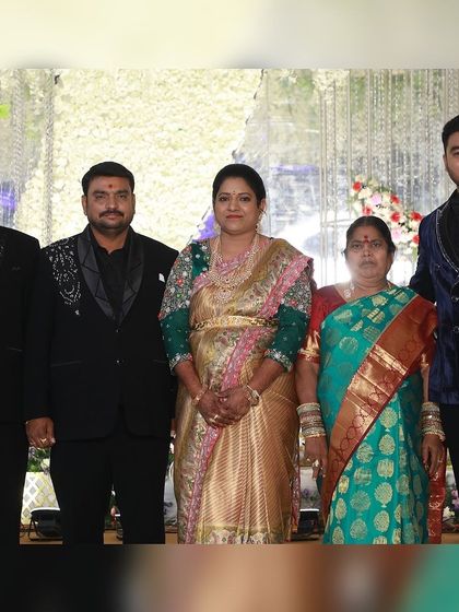 A family dressed in our coordinated formal wear for a reception. The men wear matching black suits with unique silver embroidery on the shoulders, creating a unified family look.
