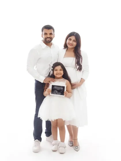 A beautiful family portrait announcing their second child. The older sister proudly holds the sonogram, making her a central part of this exciting new chapter.
