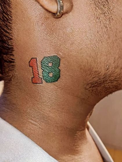 A small neck tattoo of the number 18, often representing Virat Kohli for cricket fans. A simple way to show support for your favorite player.