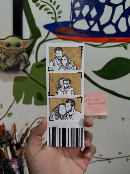A finished photo strip bookmark held in hand. The barcode at the bottom is a fun little detail I add to give it that authentic photo booth feel.