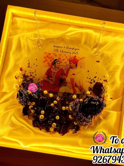 The same hanging plaque, but this time with the LED backlight turned on. The warm glow illuminates the preserved flowers, creating a magical and romantic ambiance.