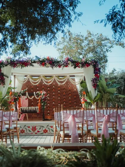 A wider perspective of the naming ceremony stage, showing the guest seating with pink chair ties that complement the floral arrangements. The design creates a festive and welcoming atmosphere.
