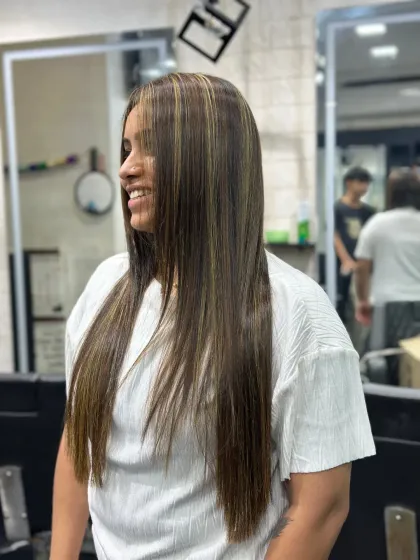 A beautiful example of long, straight hair with subtle blonde highlights. This look is modern, chic, and adds dimension without being overpowering.