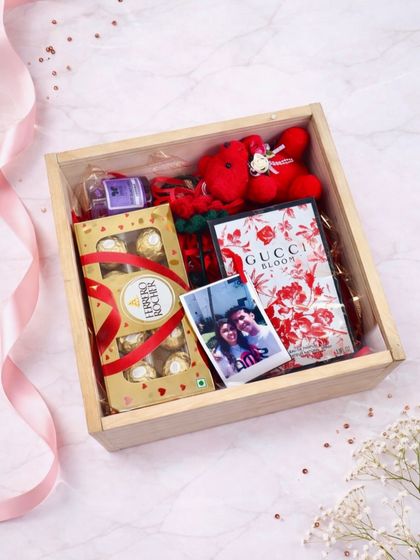 A simple and sweet Valentine's hamper in a wooden pinewood box. It contains Ferrero Rocher chocolates, a Gucci Bloom perfume, a small teddy, and a polaroid photo.