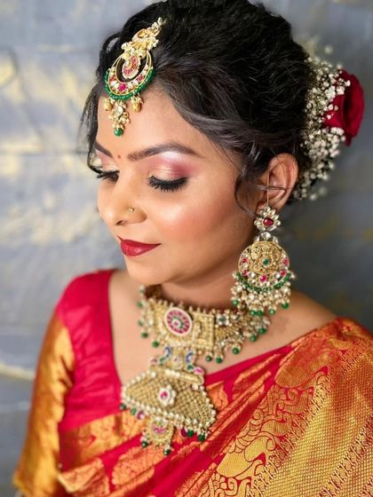 A close-up of a beautiful bride wearing a rented temple jewellery set with multi-color stones, perfectly matching her red and gold silk saree.
