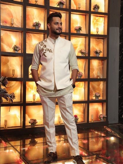 A client looking sharp in our off-white Indo-Western set. The ensemble includes a kurta, trousers, and a matching Nehru jacket with delicate floral embroidery on the shoulder.
