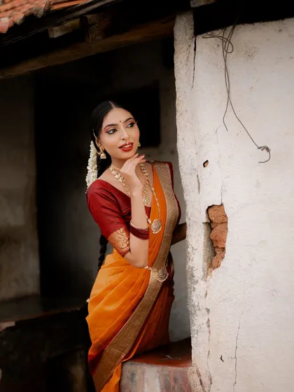 A beautiful portrait of a model in a traditional saree, framed by a rustic doorway. Her expression and the setting combine to create a classic and elegant photograph.