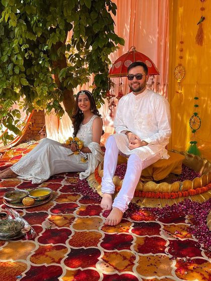 A serene moment of the couple at their Haldi ceremony. Dressed in coordinated white outfits, they look peaceful and happy, ready for the rituals to begin.