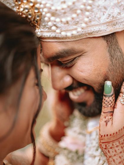 A close-up on the groom's joyful face as his bride holds his cheek, a moment of pure love.