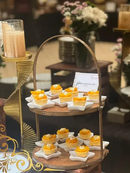 Adorable mini mango cheesecakes served on star-shaped plates and displayed on a two-tiered wooden stand. A seasonal favorite.