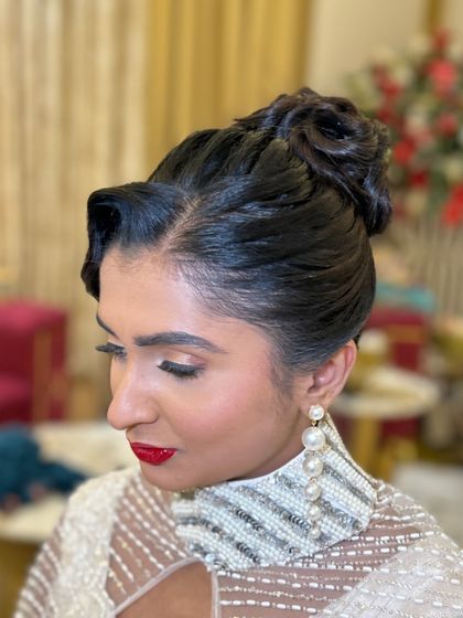 A vintage-inspired updo with a sculpted wave at the front and a high bun, perfect for a themed event or a bride wanting a retro look.