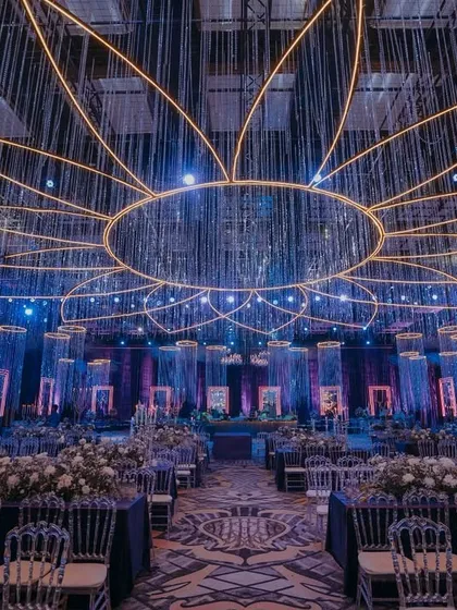 For this sangeet, I envisioned a celestial world. The design is built around dramatic lighting, with a massive, lotus-shaped neon installation and cascading crystal strings that mimic a starry sky. This demonstrates how I use light and structure to transform a large ballroom into an intimate, high-energy environment for celebration.