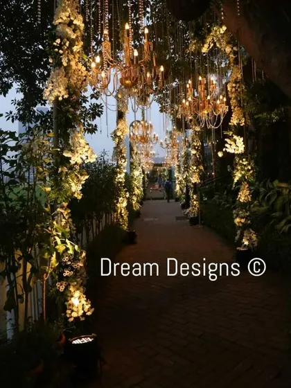 An ethereal walkway perfect for a sophisticated evening event. The path is lined with illuminated floral arrangements, with dozens of crystal chandeliers hanging overhead like a starry sky.