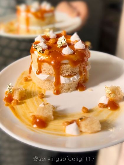 A plated slice of my vanilla caramel cake. It's a layered vanilla sponge with a rich, gooey caramel drip, meringue kisses, and edible gold leaf for a touch of elegance.