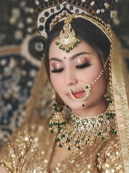 A bride in a golden sequin lehenga with a green and gold Kundan set. The closed-eye pose creates a serene and beautiful portrait.