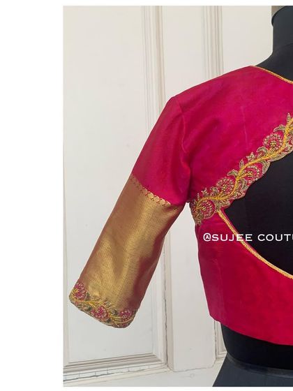 A side view of the pink and gold blouse, showing the clean finish of the back cutout and the simple embroidery on the sleeve cuff.