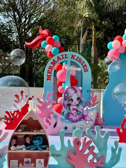 A cute mermaid sits in a boat-like prop, with 'Mermaid Kisses' written on the side.