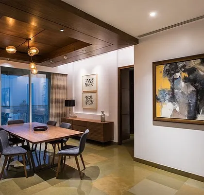 A dining room designed for an art lover. The space uses a neutral color palette and clean lines, allowing the vibrant artwork to take center stage. The wooden ceiling adds warmth and texture, balancing the modern furniture.
