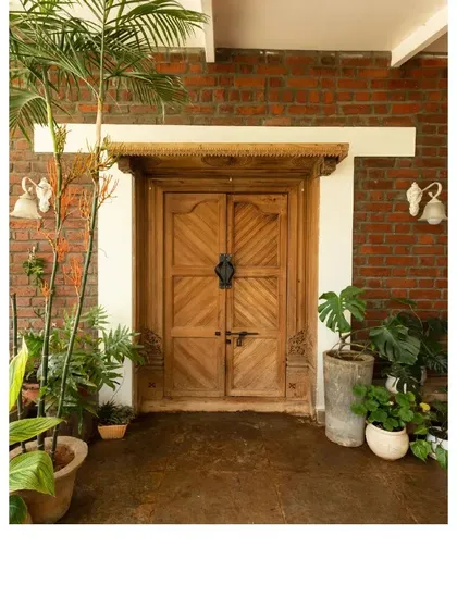 This main entrance features a repurposed vintage door set against an exposed brick wall. We believe details like these add a sense of history and character, making a new house feel like a home with a story.
