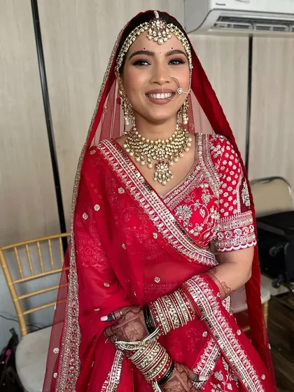 The complete traditional bridal look. This bride is radiant in her red lehenga, with perfectly draped dupatta, intricate jewelry, and makeup that highlights her joyful smile.