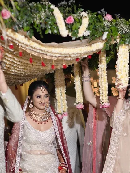 Another angle of the bride's entry, capturing her happy expression as she walks under the canopy held by her family. It’s a moment filled with tradition and emotion.
