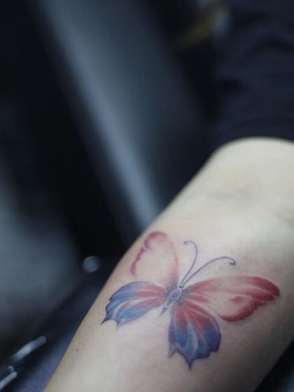 Another angle of the watercolor butterfly tattoo, showing how the colors blend and fade into the skin.