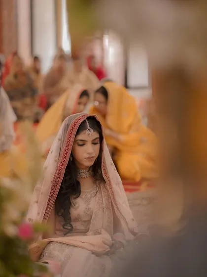 A quiet, contemplative moment for the bride during the Anand Karaj. This artistic shot captures her serene beauty amidst the ceremony.