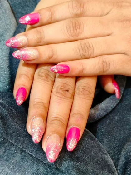 A vibrant pink glitter ombre on pointed nails, perfect for a party or festive event.