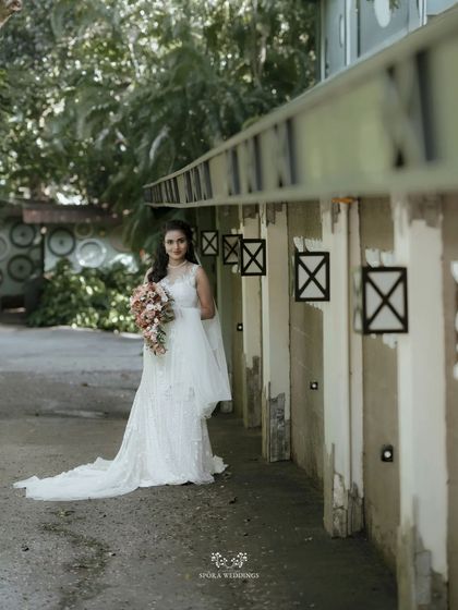 A full-length shot of the bride in her stunning white gown, standing in a rustic, industrial-style corridor.