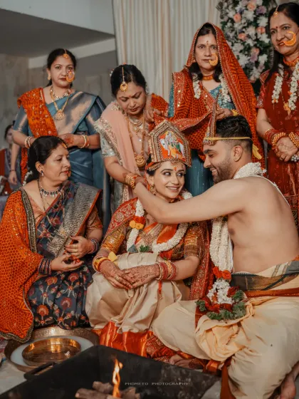 The groom places the sacred necklace, a pivotal moment in the ceremony, surrounded by the watchful eyes of their family.